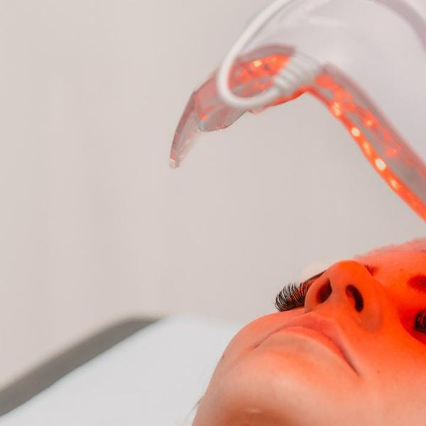 Clinician performing red light therapy facial treatment using handheld device for skin rejuvenation