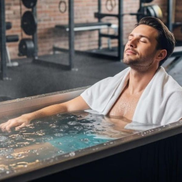 Man relaxing in a cold plunge tub at the gym, showing cold water immersion as part of a pre-workout routine