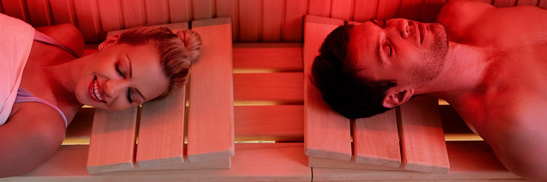 Man and woman relaxing in infrared sauna with red light therapy to boost recovery and cellular energy