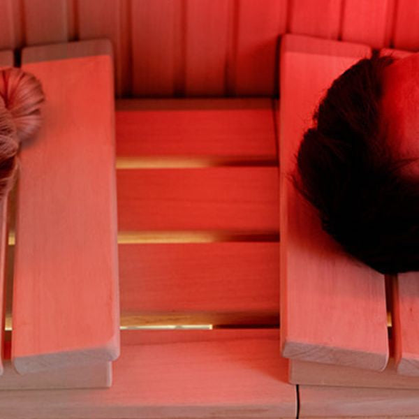 Man and woman relaxing in infrared sauna with red light therapy to boost recovery and cellular energy