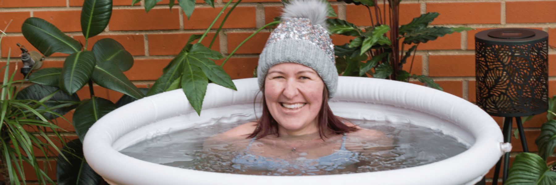 Person wearing a wool hat while relaxing in an outdoor ice bath tub during cold plunge recovery session