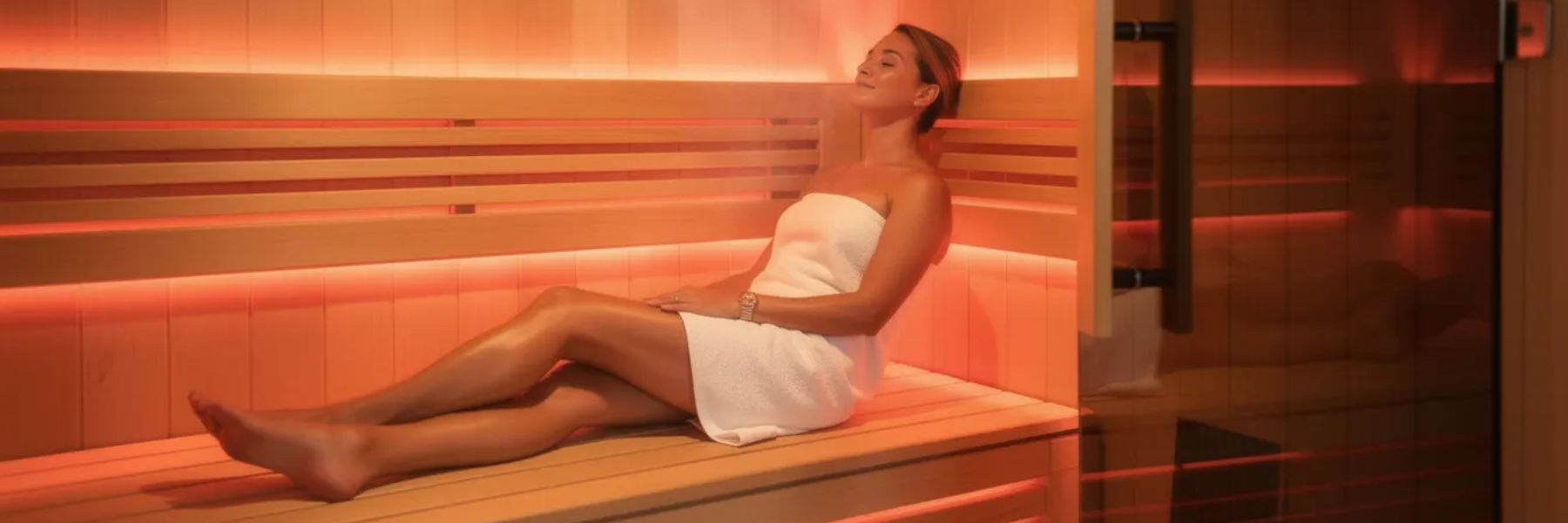 Woman relaxing in infrared sauna with red light therapy for muscle recovery and skin rejuvenation