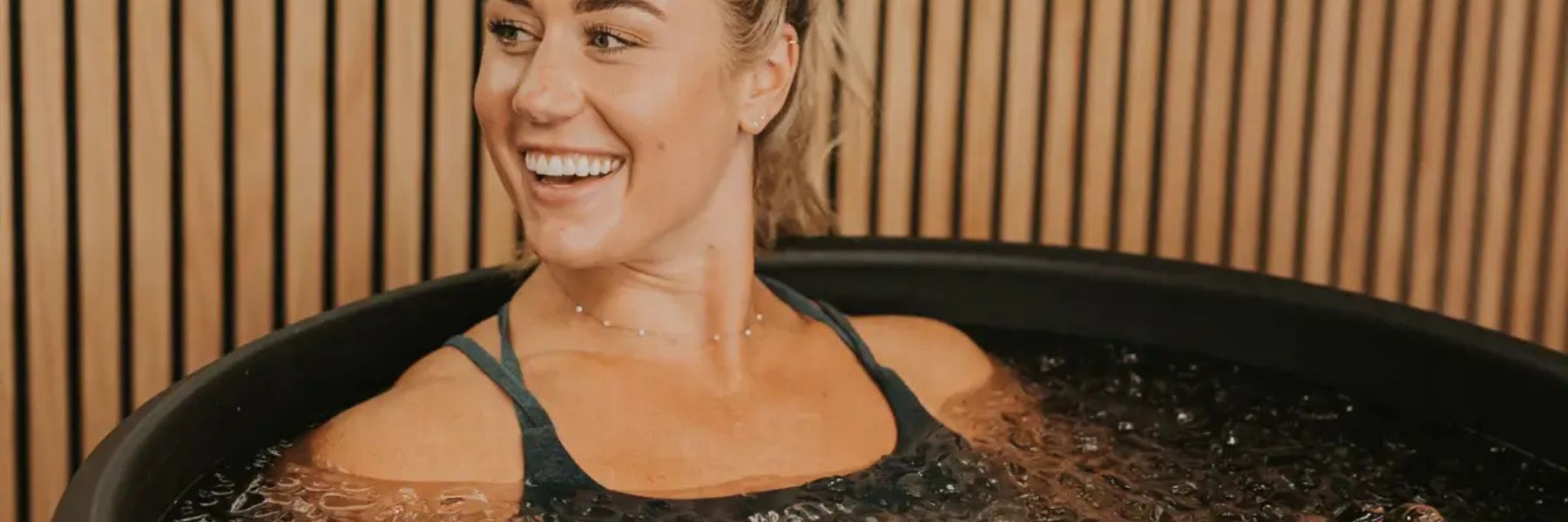 Woman relaxing in a modern cold plunge tub during an ice bath session for recovery and metabolic health benefits.