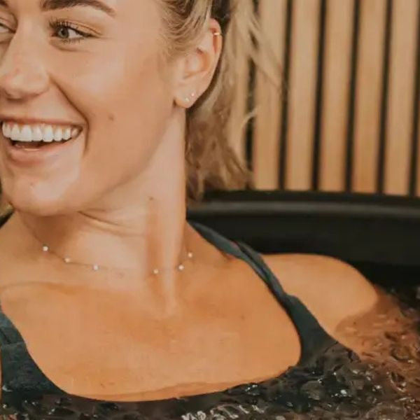 Woman relaxing in a modern cold plunge tub during an ice bath session for recovery and metabolic health benefits.