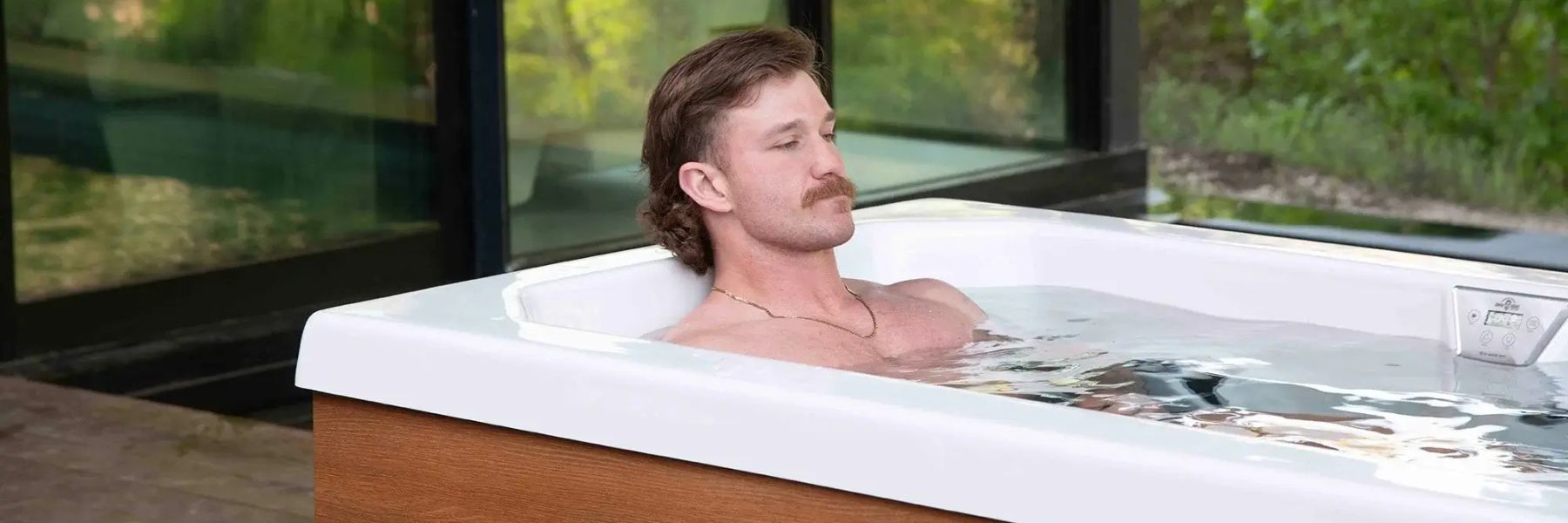 Man relaxing in a modern outdoor Cold Plunge Tub filled with cold water as part of ice bath therapy for recovery and headache relief.