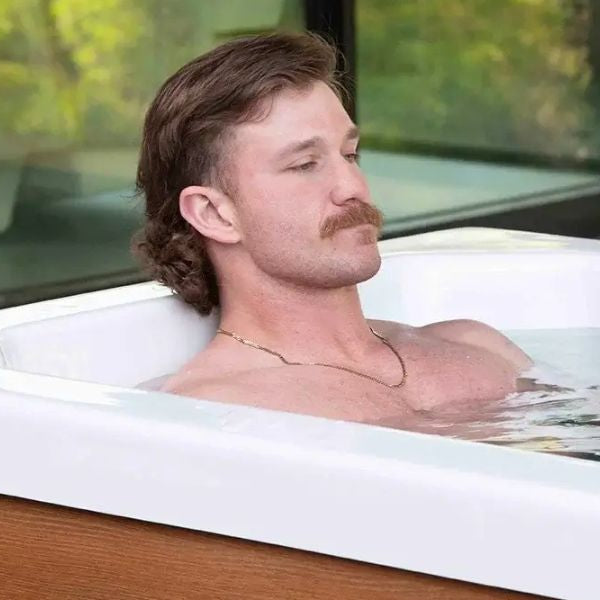 Man relaxing in a modern outdoor Cold Plunge Tub filled with cold water as part of ice bath therapy for recovery and headache relief.