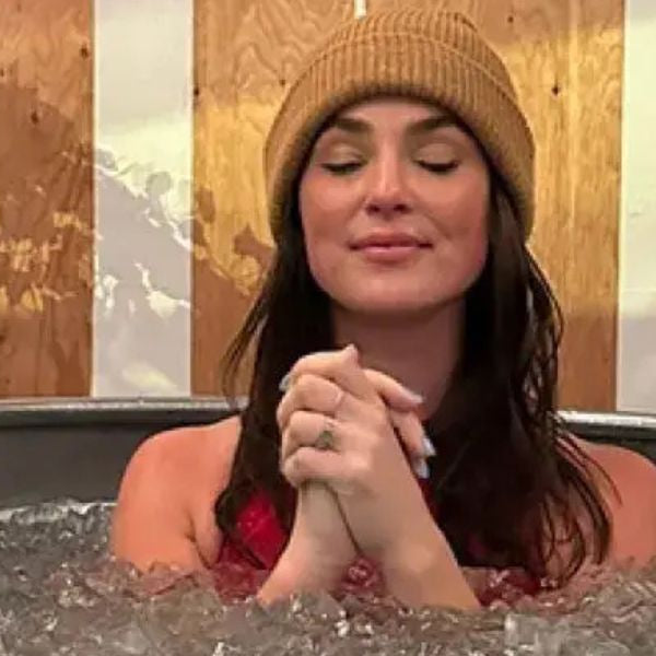 Woman relaxing in an ice bath tub filled with ice during a cold plunge therapy session for recovery and mental clarity.