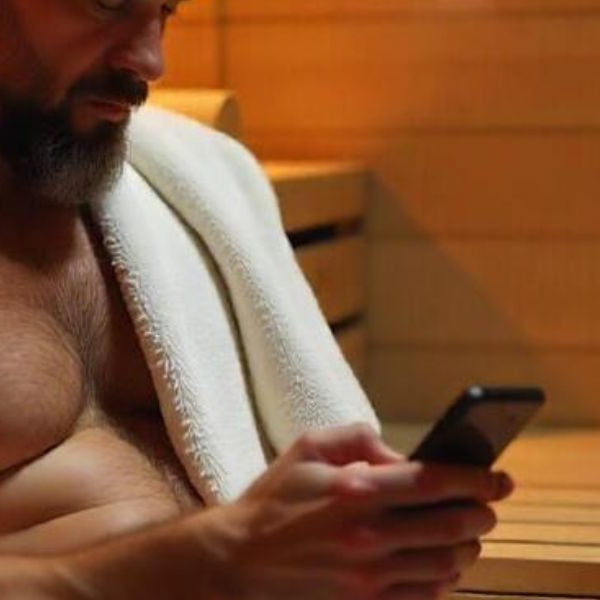Man using smartphone in sauna illustrating moisture and heat risks for electronic devices