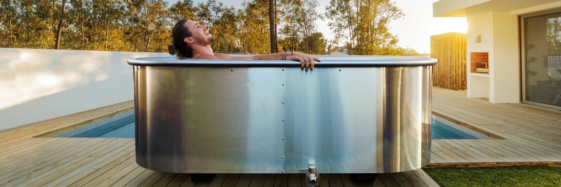 Man relaxing in a stainless steel cold plunge tub outdoors, highlighting modern ice bath design and recovery benefits