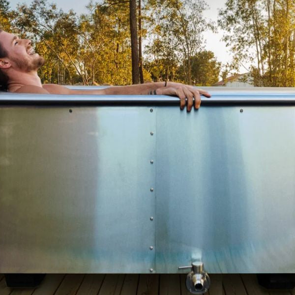 Man relaxing in a stainless steel cold plunge tub outdoors, highlighting modern ice bath design and recovery benefits