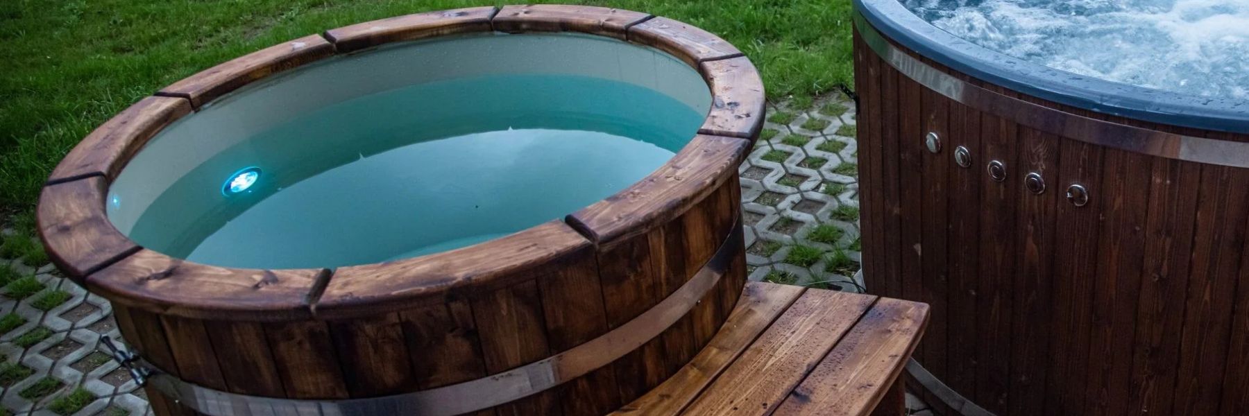 Outdoor wooden cold plunge tub filled with cold water next to a hot tub in a garden wellness setup.