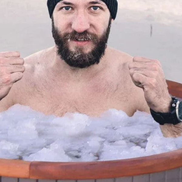 Man practising controlled breathing while sitting in an ice bath tub as part of a cold plunge recovery routine.