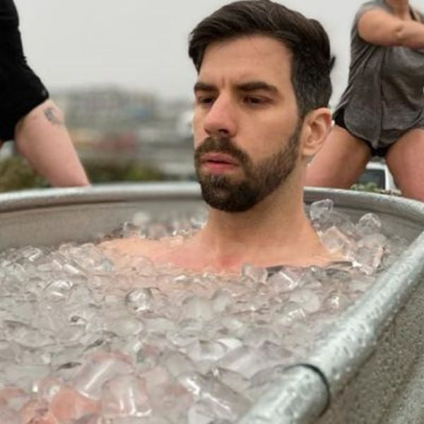 Athlete sitting in an outdoor ice bath tub during a cold plunge session for recovery and calorie burning.
