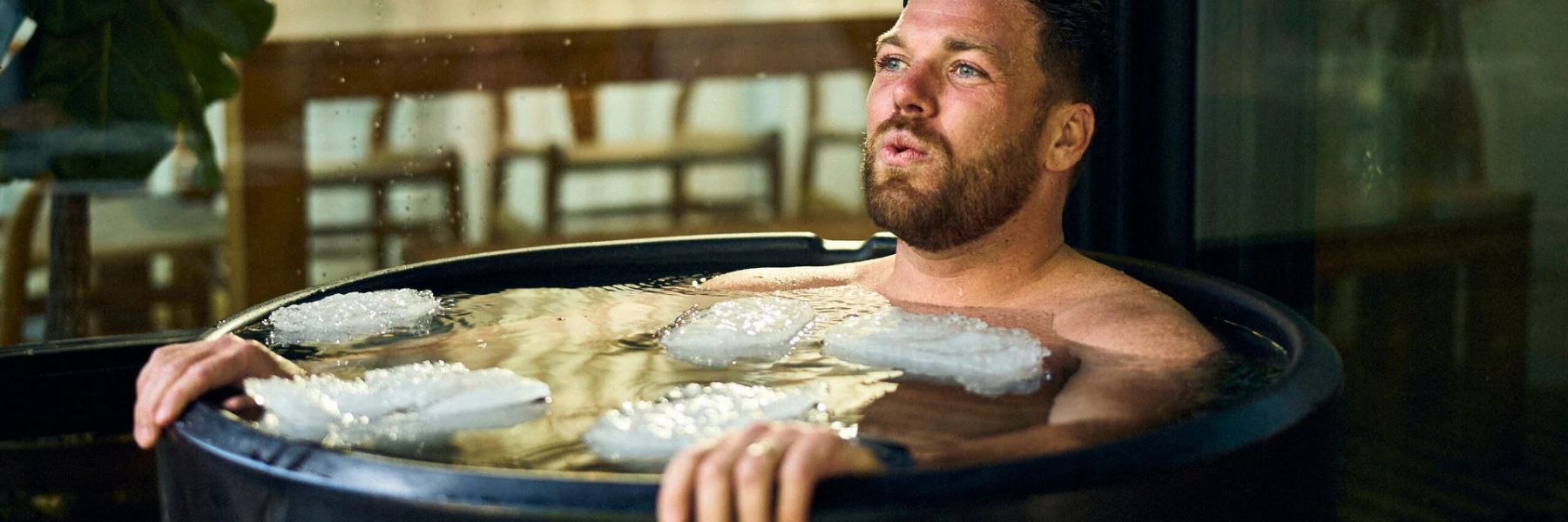 Person practising controlled breathing while sitting in a cold plunge tub.