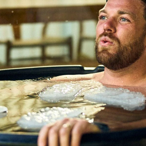 Person practising controlled breathing while sitting in a cold plunge tub.