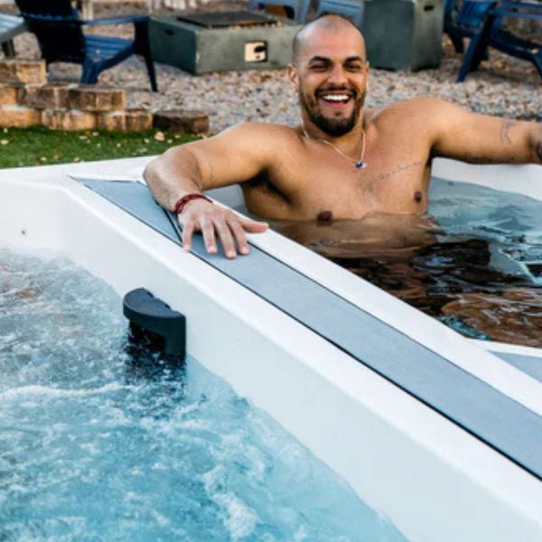 Person slowly entering a cold plunge tub outdoors while practising controlled breathing during an ice bath recovery session.