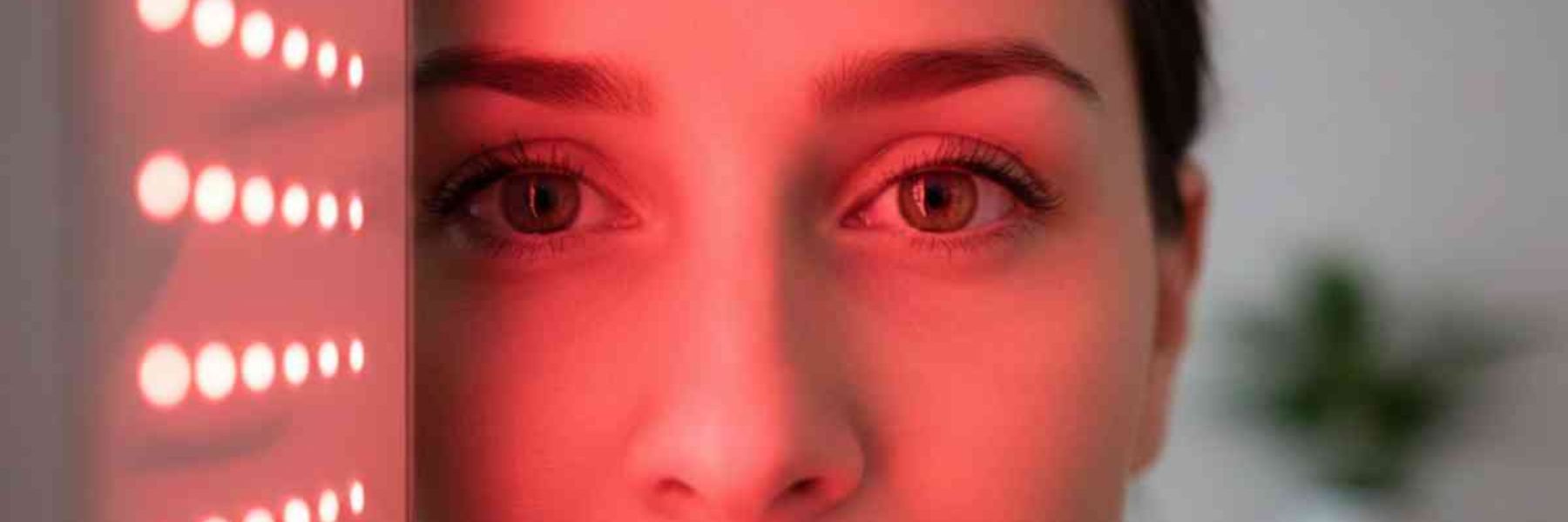 Close-up of woman using red light therapy device for facial treatment and skin rejuvenation