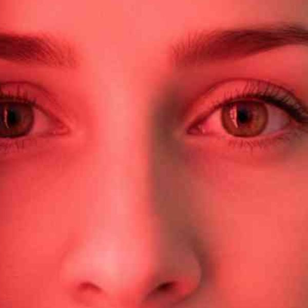 Close-up of woman using red light therapy device for facial treatment and skin rejuvenation