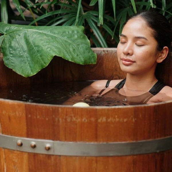 Adult athlete using an ice bath tub for cold plunge recovery therapy after exercise.