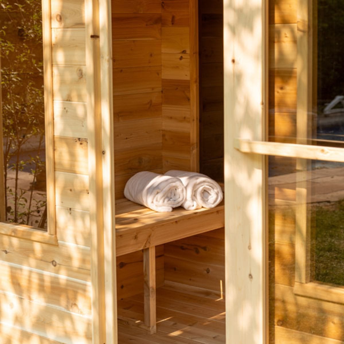 Wooden sauna with towels on a bench, surrounded by natural light
