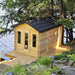 Wooden cabin by a body of water with trees in the background
