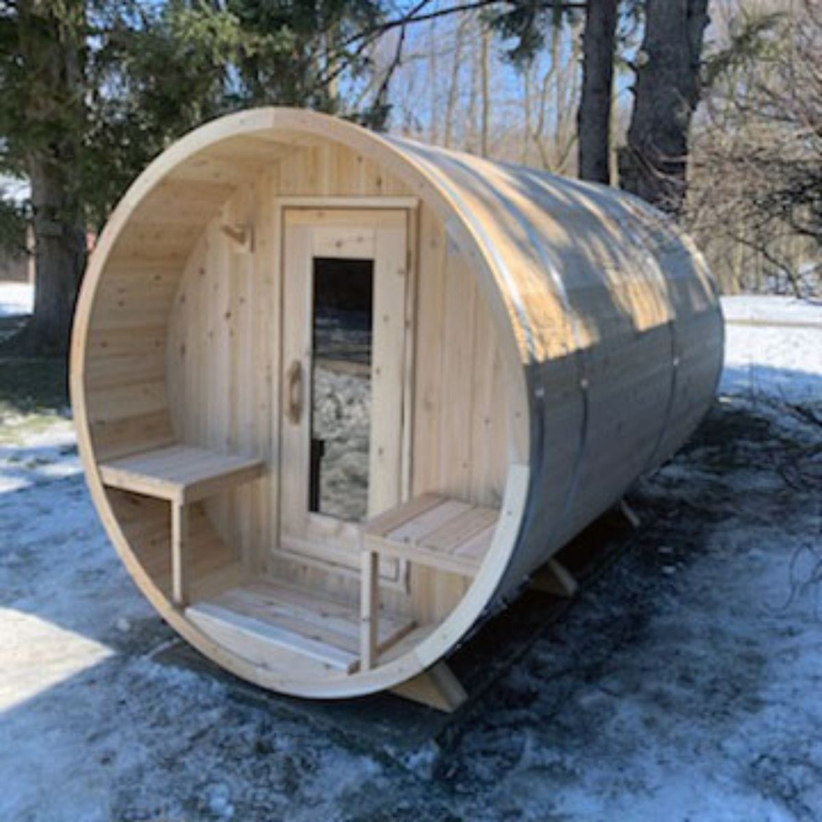 Wooden barrel-shaped sauna in a snowy outdoor setting