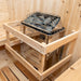 Wooden sauna shelf with metal grill and rocks inside a wooden sauna.