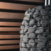 Decorative stone column with metal cage and 'HUUM' branding against a wooden slat background