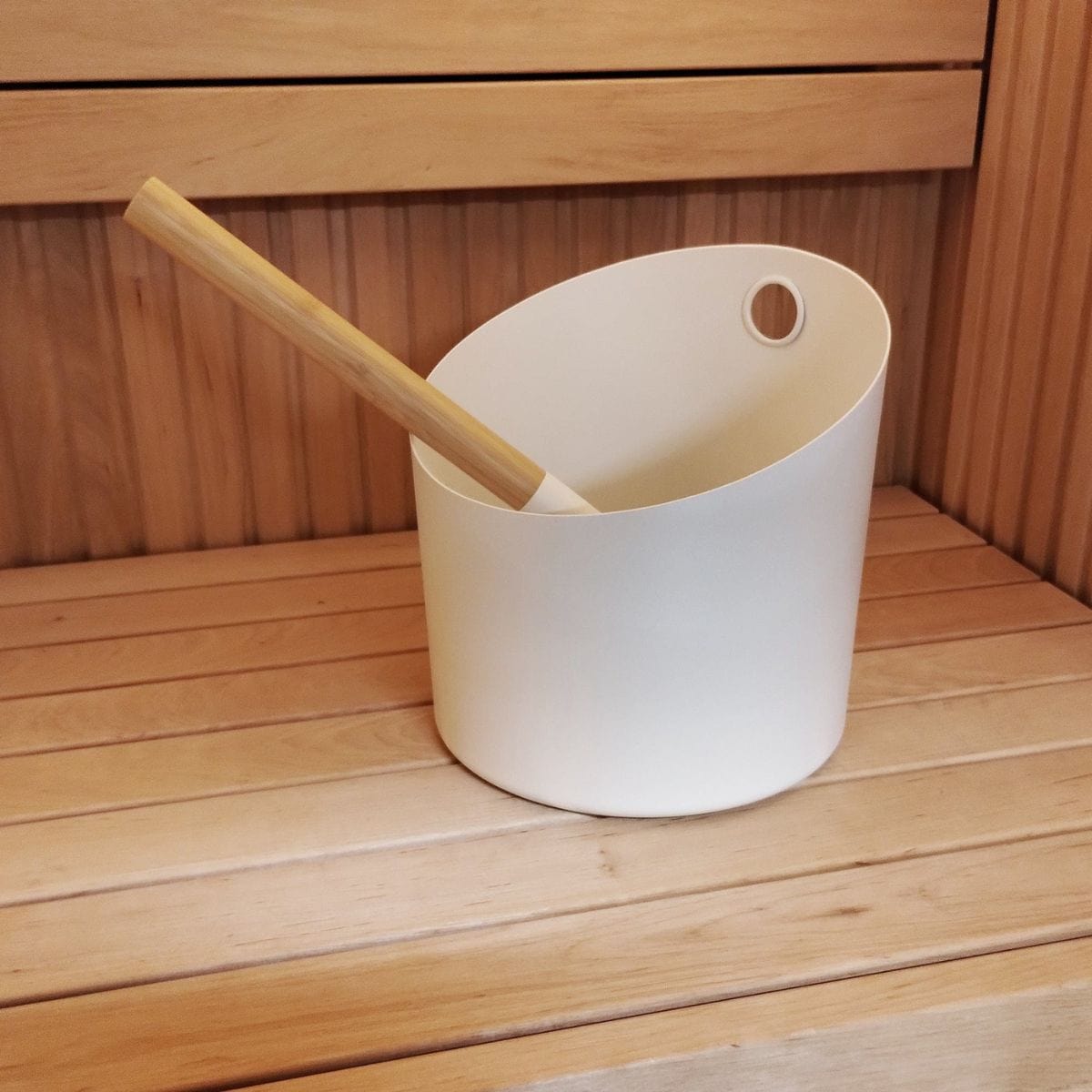 White bucket with a wooden handle on a wooden surface