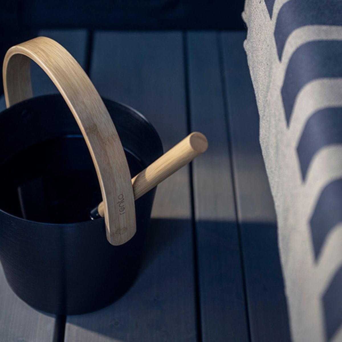 Black bucket with wooden handle on a dark wooden surface