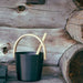 Black bucket with wooden handle and ladle against a wooden background