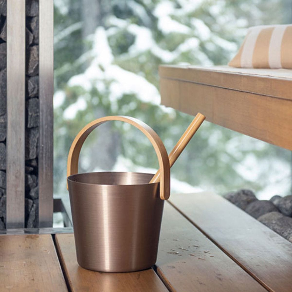Bronze bucket with wooden handle on a wooden surface outdoors