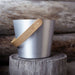 Metallic container with a wooden handle on a wooden surface