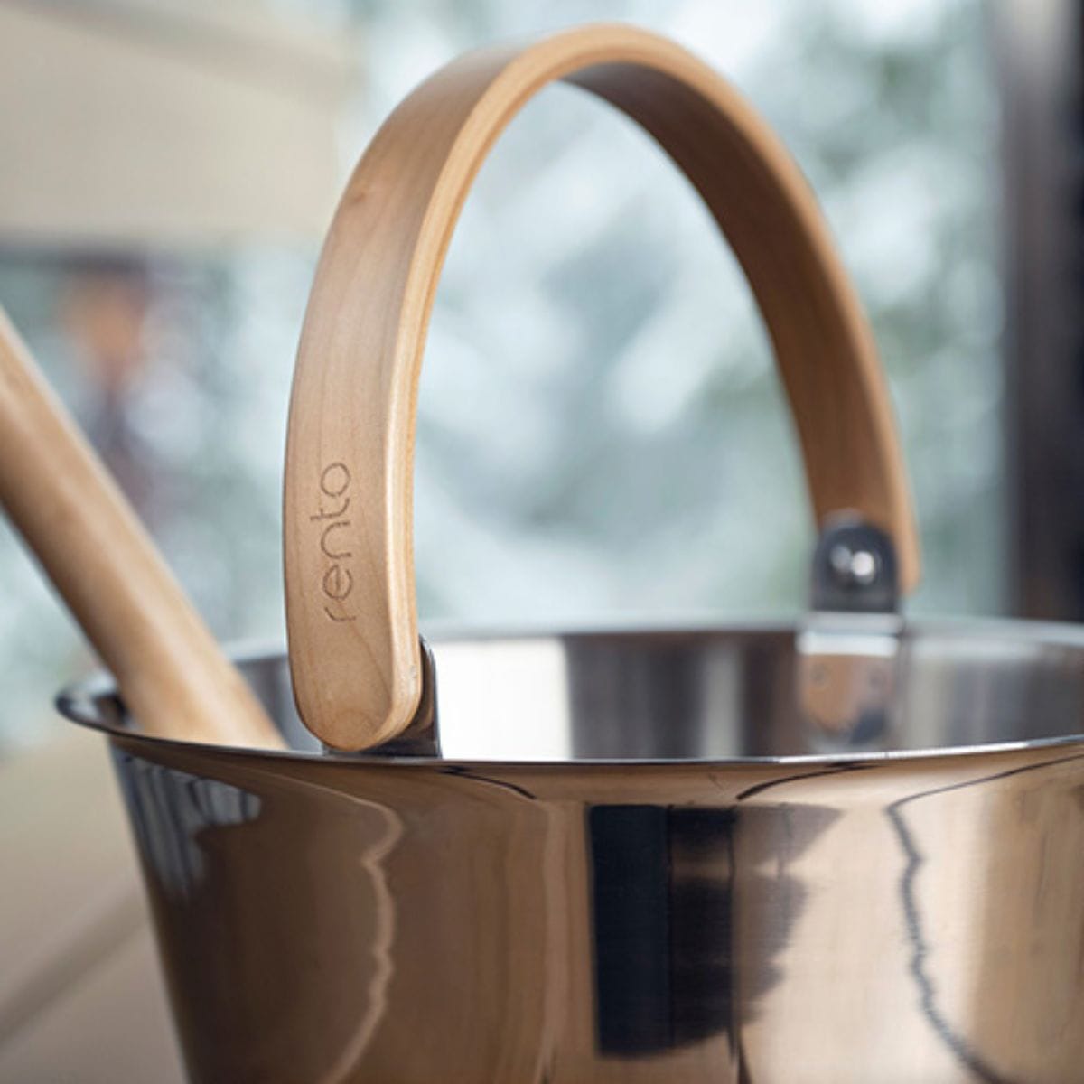 Stainless steel pot with wooden handle on a blurred background