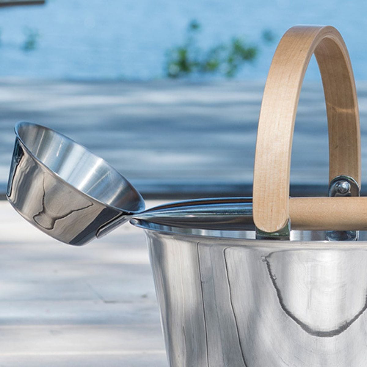 Metal bucket with wooden handle against a blurred natural background
