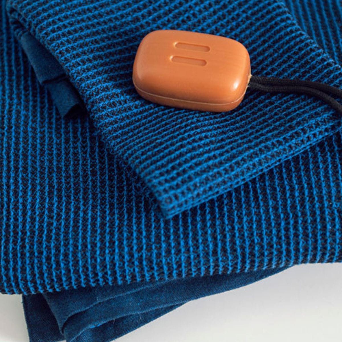 Blue textured blanket with a brown rectangular object on top