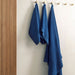 Three blue towels hanging on a rack against a neutral wall.