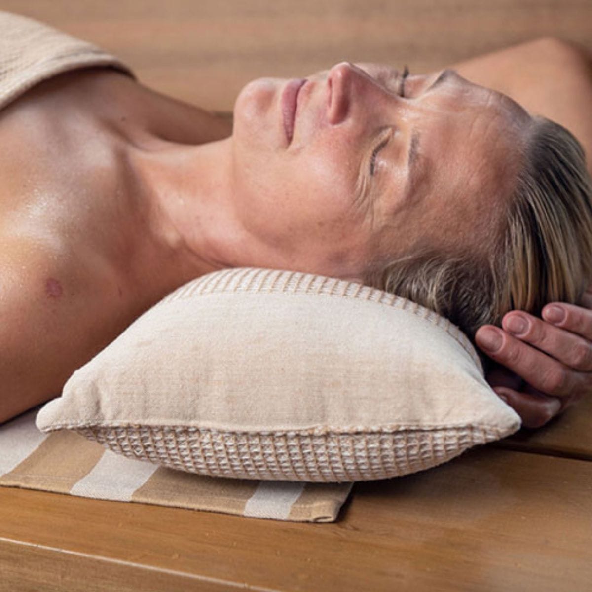 Person lying on a massage table with a pillow under their head