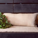 Beige woven cushion on a wooden bench with greenery