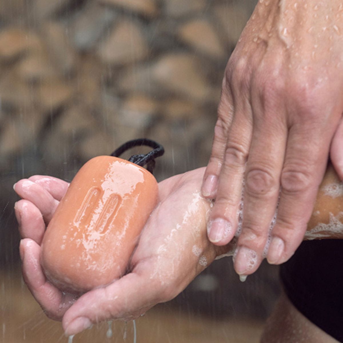 Person washing hands with a bar of soap outdoors
