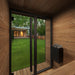 Wooden cabin interior with a view of a garden through glass doors.