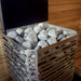 Metal basket filled with stones against a wooden wall