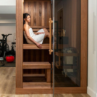Bather on the upper bench of the CT Element Nook, seen through the open glass door in a home gym